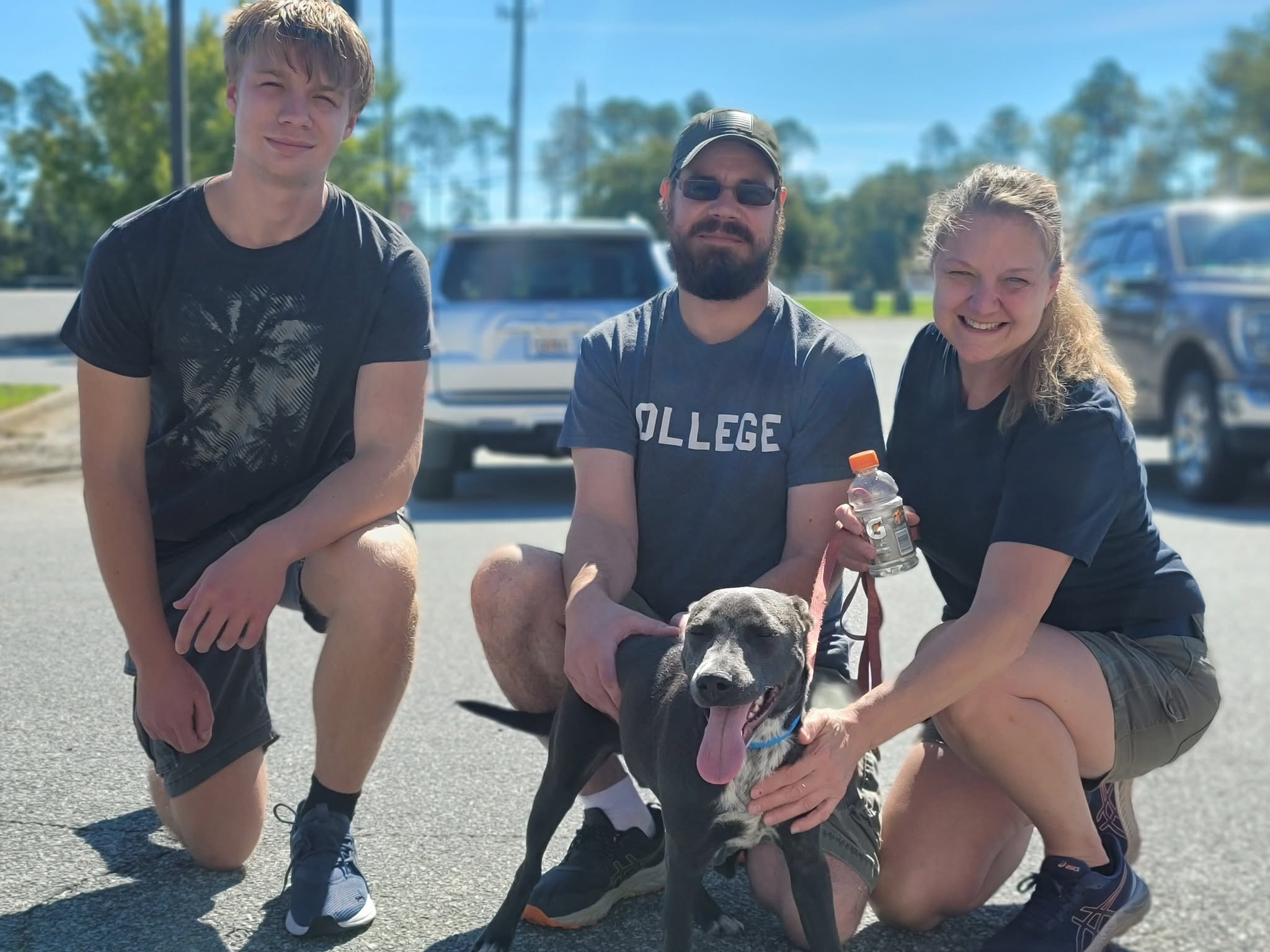 A happy family kneeling with their newly adopted blue lab mix